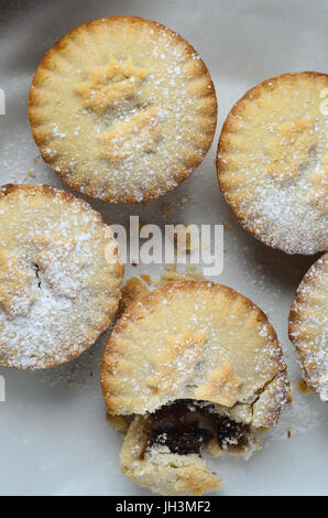 Eine Gruppe von vier Weihnachten Mince Pies, geschossen von oben mit einem aufgebrochen, Füllung verfügbar zu machen. Stockfoto