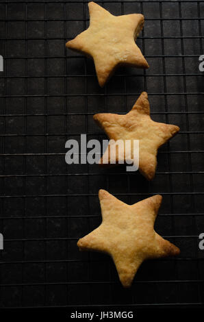 Aufwand für drei Sterne geformt Weihnachten Kekse (Cookies) auf schwarzen Draht Kühlregal, auf der rechten Seite des Rahmens. Stockfoto