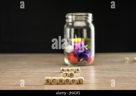 Zurück zur Schule geschrieben in Holzblöcke mit ein Glas mit Push-pins Stockfoto
