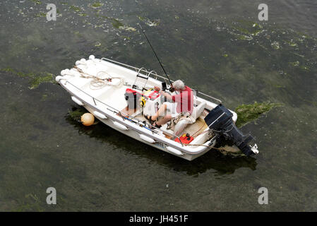 Überblick über einen Mann in einem Boot seine Rute und Schnur für einen Angelausflug vorbereiten Stockfoto