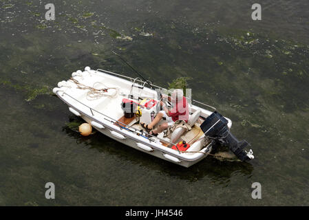 Überblick über einen Mann in einem Boot seine Rute und Schnur für einen Angelausflug vorbereiten Stockfoto