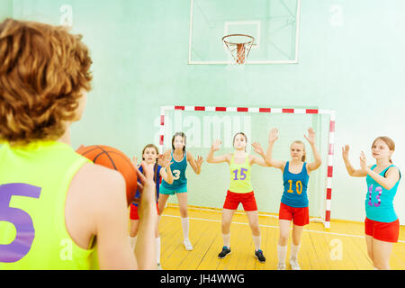 Porträt von Basketball-Spieler wirft den Ball in den Korb während seiner Gegner verteidigen den Reifen Stockfoto