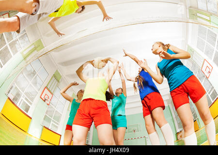 Unteransicht des teenage Volleyball-Spieler dienen den Ball während des Spiels in gymnasium Stockfoto