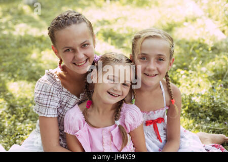 Drei Mädchen sitzen auf dem Rasen und Lächeln Stockfoto