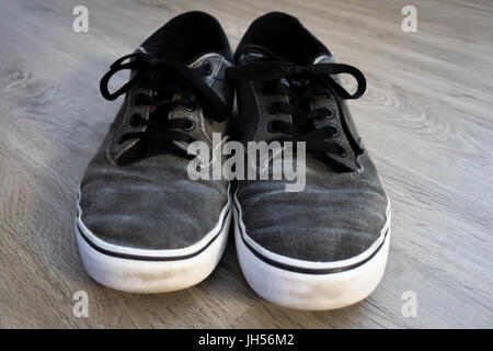 Ein paar graue Turnschuhe sitzen auf einer Vinyl-Dielenboden. Stockfoto