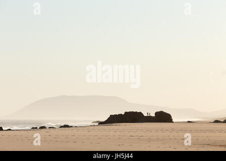 Zwei Menschen beim erkunden, einen schönen Strand und die Küste im goldenen Abendlicht in Australien Silhouette. Stockfoto