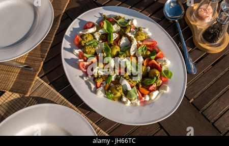 Caprese Salat mit Pesto und kalte gekochte Kartoffeln, auf weissem Geschirr serviert, auf Garten Terrasse Tisch im Sommer Sonnenschein, Schottland, UK Stockfoto