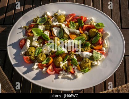 Caprese Salat mit Pesto und kalte gekochte Kartoffeln, auf weissem Geschirr serviert, auf Garten Terrasse Tisch im Sommer Sonnenschein, Schottland, UK Stockfoto