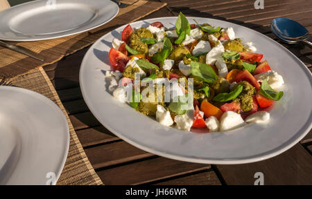 Caprese Salat mit Pesto und kalte gekochte Kartoffeln, auf weissem Geschirr serviert, auf Garten Terrasse Tisch im Sommer Sonnenschein, Schottland, UK Stockfoto