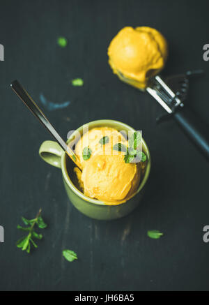 Mango-Sorbet Eisportionierer mit Minze, schwarz Holz Hintergrund Stockfoto