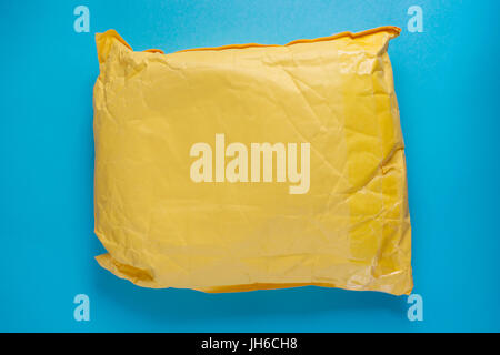 Gelbe Post Kartonverpackung auf blauem Hintergrund. Textfreiraum auf der Verpackung Stockfoto