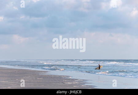 Am frühen Morgen Strandszene in Ponte Vedra Beach, Florida als senior Surfer wird das Wasser nach einer belebenden Sunrise Surf-Session beendet. Stockfoto