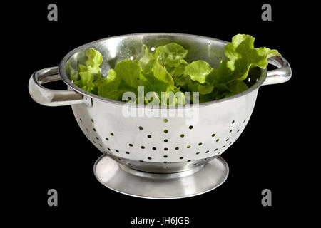 Ein Sieb, oder küchensieb, dargestellt mit Salat vor einem schwarzen Hintergrund Stockfoto
