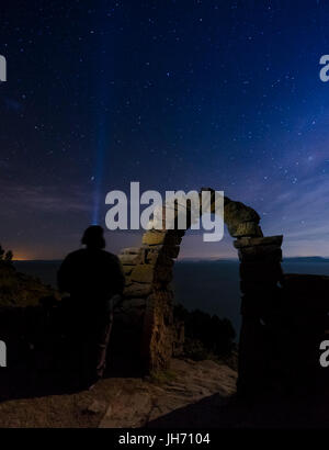 PUNO, PERU - ca. Oktober 2015: Mann sucht den Himmel und die Sterne mit einem typischen Bogen von der Insel Taquile im Titicacasee. Stockfoto