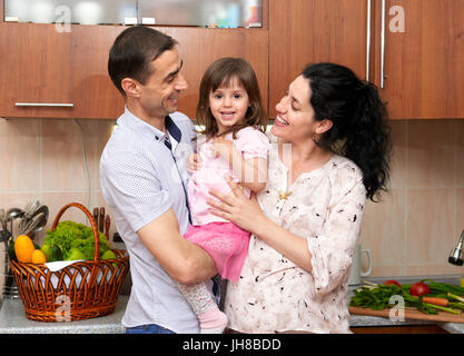 Familienbild in Küche Interieur mit frischem Obst und Gemüse, gesunde Ernährung Konzept, schwangere Frau, Mann und Kind Mädchen Stockfoto