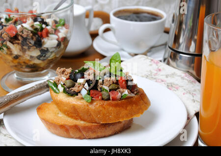 Frühstück von gebratenen Toast mit gehackten Thunfisch mit Ei, Würfel von Tomaten und Oliven Scheiben, Kapern mit einer Tasse Kaffee, eine Kaffeekanne auf einem Tablett Stockfoto