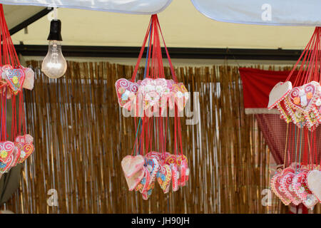 Lebkuchenherz Herzen hängen auf Garn Stränge.  Eine weißglühende Glühlampe ist auch sichtbar auf dem Foto. Stockfoto