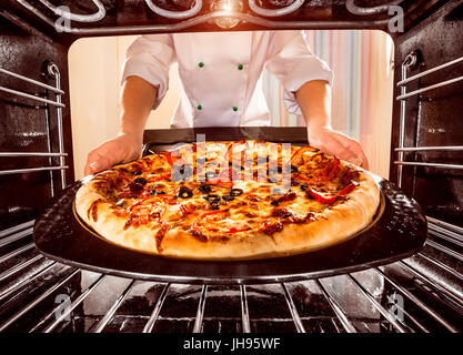 Chefkoch Pizza in den Ofen, Blick aus dem Inneren des Ofens. Kochen in den Ofen. Stockfoto