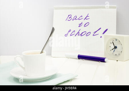 Zurück zur Schule Nachricht geschrieben am Notebook-Konzept. Set mit Wecker und eine Tasse Kaffee am Morgen. Kopieren Sie Raum. Weißen Hintergrund. Stockfoto