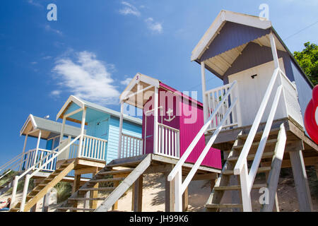 Reihen von bunten Strandhütten auf Stelzen am sonnigen, sandigen Strand von Wells nächsten The Sea in Norfolk, England ist ein beliebtes touristisches Strand in England. Stockfoto