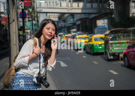 Chinesische Frau am Telefon sprechen während des Gehens auf Straße, Bangkok Thailand. Intelligente Backpacker mit mobile app außerhalb. Gerne Asiatin aufrufenden duri Stockfoto