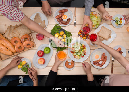 Abendessen mit Freunden genießen.  Draufsicht der Gruppe von Menschen, die Abendessen zusammen beim Sitzen am Tisch aus Holz Stockfoto