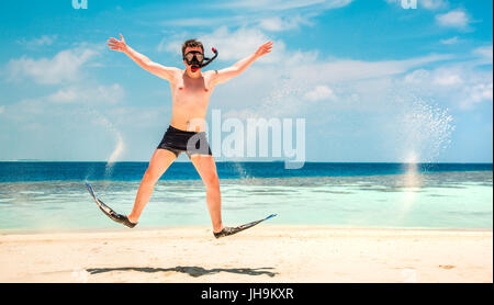 Lustiger Mann springt in Flossen und Maske. Urlaub an einem tropischen Strand auf den Malediven Inseln. Stockfoto