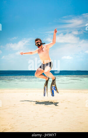 Lustiger Mann springt in Flossen und Maske. Urlaub an einem tropischen Strand auf den Malediven Inseln. Stockfoto