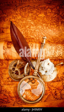 Vintage Kompass, Lupe, Taschenuhr, Federkiel, Spyglass liegen auf einer alten antiken Karte 1565 mit eine brennende Kerze. Vintage Stillleben. Stockfoto