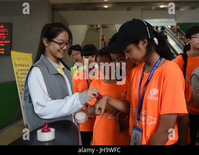 (170713)--Peking, 13. Juli 2017 (Xinhua)--A Mädchen freiwilliger (L) aus Beijing No. 2 Middle School Stempel auf einer Seite eines Besuchers in China Science und Technology Museum in Peking, Hauptstadt von China, 13. Juli 2017. Während dieser Sommerferien bietet Beijing No. 2 Middle School Möglichkeiten für Studenten zur Teilnahme an verschiedenen Aktivitäten der sozialen Praxis. (Xinhua/Li Wen) (Zx) Stockfoto