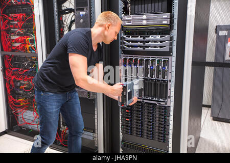 Mitte erwachsenen männlichen Computer Engineer Installation Blade-Server im Gehäuse im Rechenzentrum Stockfoto