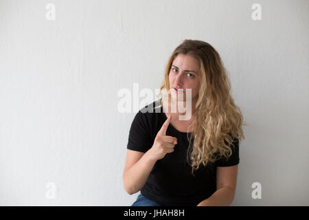 Young, drückt blonde, Kaukasische Frau, negative Emotionen, Wut, schreien und Fingerzeig auf Zuschauer und Fotografen auf einem weißen Hintergrund. Stockfoto