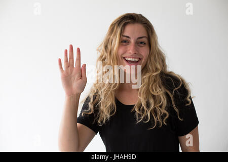 Jung, blond, schön, kaukasischen Milennial Frau zum Ausdruck bringen Aufregung und Glück während winken vor einem weißen Hintergrund. Einladend, begrüßen. Stockfoto