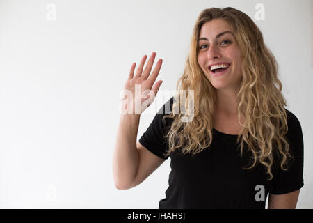 Jung, blond, schön, kaukasischen Milennial Frau zum Ausdruck bringen Aufregung und Glück während winken vor einem weißen Hintergrund. Einladend, begrüßen. Stockfoto