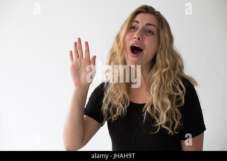 Jung, blond, schön, kaukasischen Milennial Frau zum Ausdruck bringen Aufregung und Glück während winken vor einem weißen Hintergrund. Einladend, begrüßen. Stockfoto
