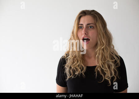 Jung, blond, schön, kaukasischen Milennial Frau zum Ausdruck bringen Aufregung und Glück während winken vor einem weißen Hintergrund. Einladend, begrüßen. Stockfoto