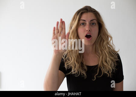 Young, drückt blonde Frau Vorsicht und Achtung Viewer nicht, weiter zu gehen. Vor einem weißen Hintergrund hält sie ihre Hand bis zum Betrachter. Stockfoto