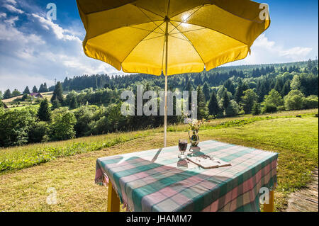 Tisch mit Tischdecke und gelben Sonnenschirm in Berg Sommer Landschaft Stockfoto