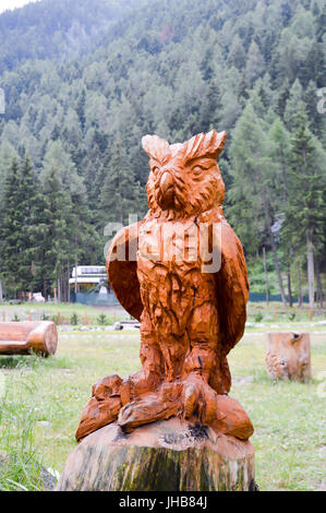 Skulptur von einer Eule auf einem Baumstamm in einem Park in den Dolomiten in Italien Stockfoto