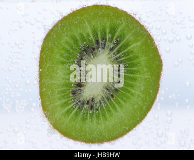 Scheibe von Kiwi in Wasser mit Luftblasen drauf Stockfoto