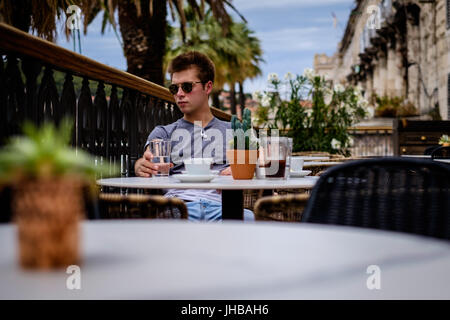 Ein junger Mann an einem Cafétisch in Split, Kroatien. Stockfoto