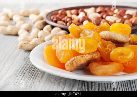 Getrockneten Früchten und Nüssen auf einem hölzernen Hintergrund. Kandierte Früchte, Zitrone, Aprikose, Feigen und Nüssen in Platte. Stockfoto