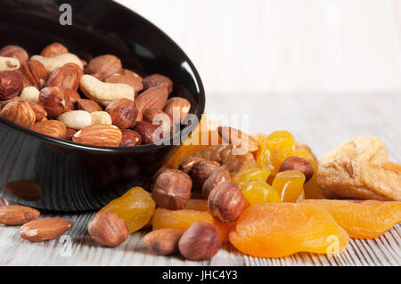 Getrockneten Früchten und Nüssen auf einem hölzernen Hintergrund. Kandierte Früchte, Zitrone, Aprikose, Feigen und Nüssen in schwarze Platte. Stockfoto