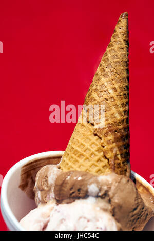 Schmelzen von Schokolade, Vanille und Beere Eiswaffel kopfüber in eine Tasse Stockfoto