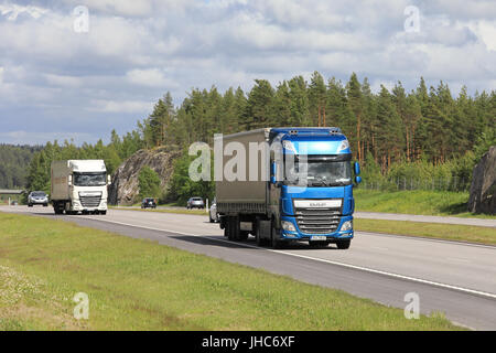 Blaue und weiße DAF XF halb Sattelzüge transportieren Güter entlang der Autobahn unter Verkehr an einem schönen Tag des Sommers. Stockfoto