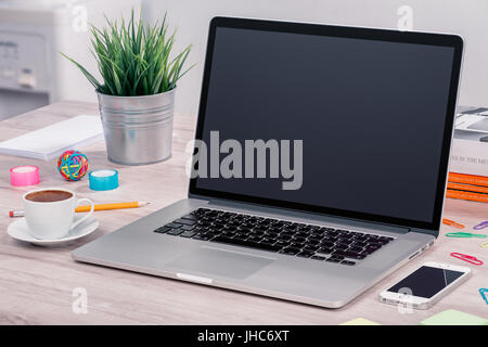 Laptop-Mock-up am Schreibtisch mit Smartphone und Tasse Kaffee Stockfoto