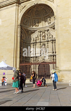 Der Portikus der Kathedrale Santa Maria de la Redonda befindet sich gegenüber der Plaza de Mercado in Logrono, Spanien, wo die Menschen in der Sommersonne im Juni spazieren oder spielen. Stockfoto
