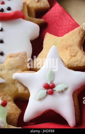 Weihnachtsgebäck (Cookies) in verschiedenen Formen, verziert mit Puderzucker (Zuckerguss).  Sternförmig im Vordergrund. Stockfoto