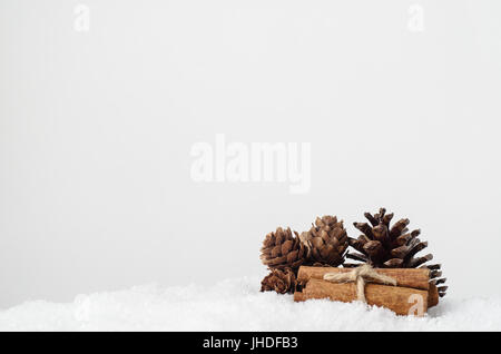 Natürliche Weihnachtsschmuck.  Tannenzapfen und Zimt-stick Bundle auf Kunstschnee mit textfreiraum oben. Stockfoto