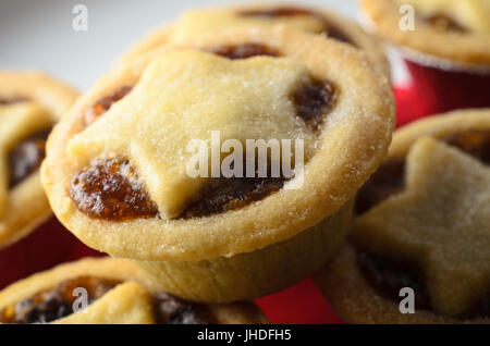 Stapel von Weihnachten Mince Pies mit Stern geformte Gebäck Tops und fruchtige Füllung ausgesetzt, auf weißen Teller mit roten Serviette. Stockfoto